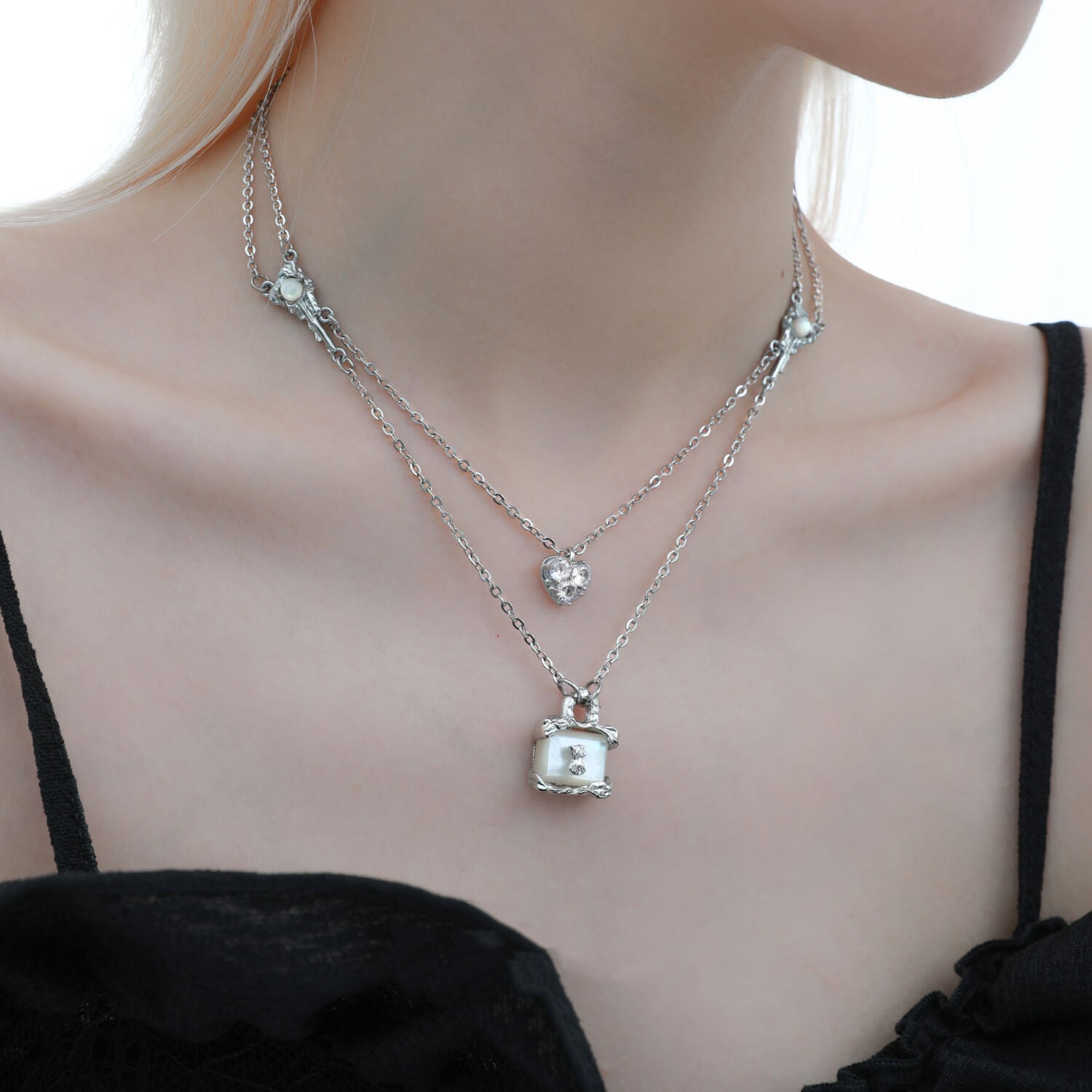Express eternal love with this unique necklace featuring a heart pendant adorned with transparent zircons and a luminous pearl lock.